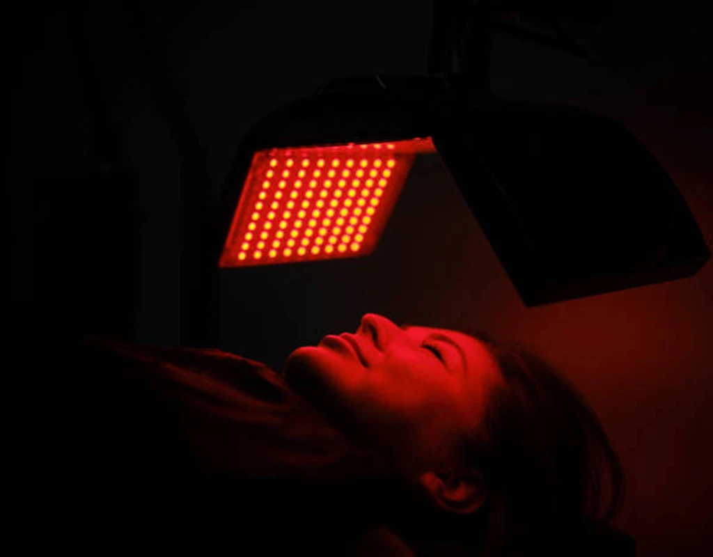 A girl takes a face light therapy.